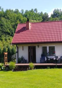 een klein wit huis met een rood dak bij Mogielicki Zakątek in Jurków