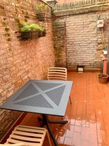 een tafel en stoelen op een patio met een bakstenen muur bij appartamento con cortile in Venetië