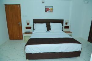 a bedroom with a large bed and a wooden door at Utsavam Hotel Apartments in Guruvāyūr