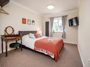 a bedroom with a bed and a desk and a window at Heath Farm House in Little Plumstead