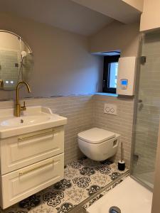 ein Badezimmer mit einem WC, einem Waschbecken und einem Spiegel in der Unterkunft Pebbles Suiten by RiNG in Regensburg