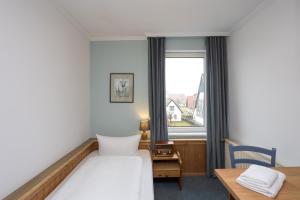 a hotel room with a bed and a desk and a window at Hotel GODEWIND in Hiddensee