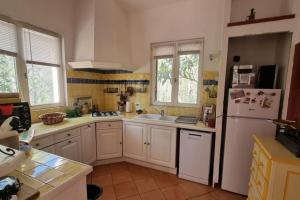 uma cozinha com armários brancos e um frigorífico branco em Maisonnette sur terrain arboré Haut Var em Villecroze