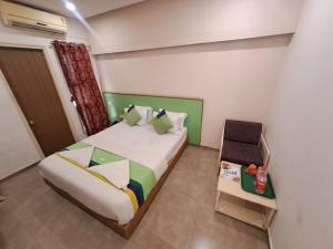 a bedroom with a bed and a chair in it at Hotel Tulsi in Vadodara