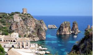 a large body of water with a lighthouse on a cliff at Dentro Scopello - Casa Vacanze in Scopello