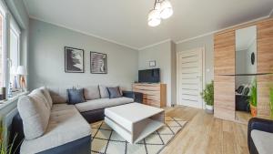 a living room with a couch and a tv at Marynarska, Sun & Snow in Rowy