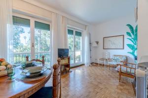 uma sala de estar com uma mesa, cadeiras e janelas em Villa Tigullio Vintage Holiday Flat em Rapallo
