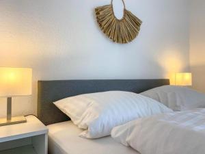 ノルトダイヒにあるSTRANDNEST NORDDEICHのベッドルーム1室(白いベッド1台、ナイトスタンド、時計付)