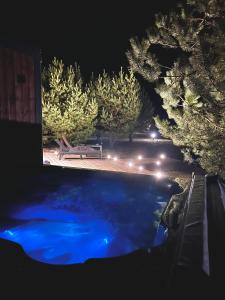 Atpūtas komplekss Pazust Priedēs - SUNSET house في بيرناتي: حمام سباحة في الليل مع مقاعد واضاءة