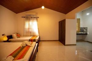 a bedroom with two beds and a window at Jim Dandy House in Tissamaharama +4 photos