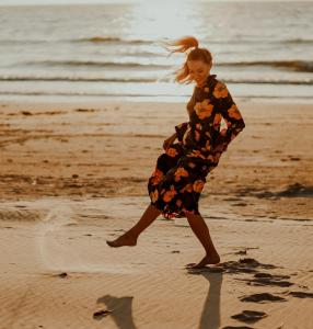 a young girl is walking on the beach at Atpūtas komplekss Pazust Priedēs - SUNSET house in Bernāti