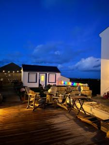 a deck with wooden tables and chairs at night at L'Atelier de Mézareun in Ouessant