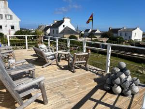 a wooden deck with chairs and a table and a fence at L'Atelier de Mézareun in Ouessant