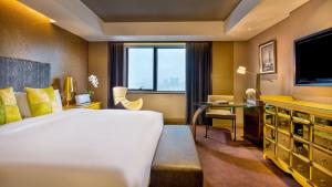 um quarto de hotel com uma cama grande e uma televisão em Sofitel Zhengzhou International em Zhengzhou