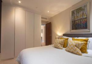 - une chambre avec un grand lit blanc et des oreillers jaunes dans l'établissement Westminster 1 bed apt with terrace, à Londres