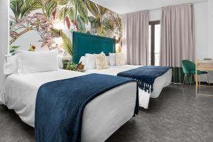 a hotel room with two beds with blue blankets at Hotel Los Girasoles in Granada