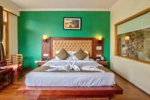a bedroom with a large bed with a green wall at Hotel Grand Oasis in Manāli