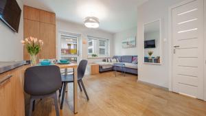 Il comprend une cuisine et un salon avec une table et des chaises. dans l'établissement Apartamenty Sun & Snow Marynarska, à Rowy