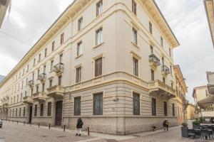 a large white building with people walking in front of it at Cinque Giornate 70 Suites by Rent All Como in Como