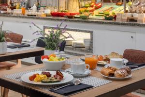 - une table avec des assiettes de produits pour le petit-déjeuner et du café dans l'établissement Catalonia Puerta del Sol, à Madrid