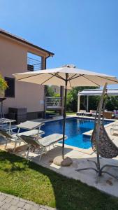 an umbrella and chairs next to a swimming pool at Apartmani Nika in Tribunj