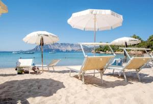 a group of chairs and umbrellas on a beach at VILLA FARFALLE CON STREPITOSA SCOGLIERA PRIVATA in Capo Coda Cavallo