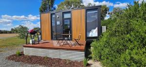 a cabin with a deck with a table and chairs at Halls Haven Tiny House 2 in Halls Gap