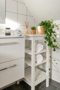 a white bathroom with white shelves and towels at Dinbnb Apartments I 100 meters from Bryggen I Self check-in I Coffee + in Bergen