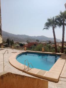 une piscine avec des palmiers et des montagnes en arrière-plan dans l'établissement Trendy Homes Envia Golf I, à La Envia