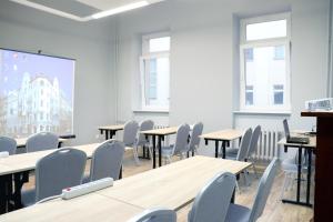 uma sala de aula com mesas e cadeiras e uma tela de projeção em Hotel Polonia Centrum em Breslávia