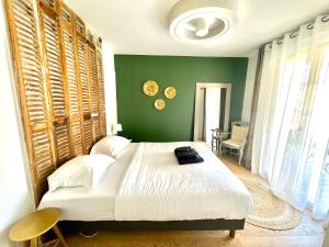 - une chambre avec un grand lit et un mur vert dans l'établissement Suite Villa Bohème, à Sainte-Marie de Ré