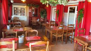 un restaurante con mesas y sillas de madera y cortinas rojas en LES MAISONS DU PATY en Arlés