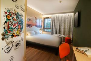 Un dormitorio con una cama blanca y una pared con pegatinas. en ibis Styles Clermont-Ferrand Aéroport en Clermont-Ferrand