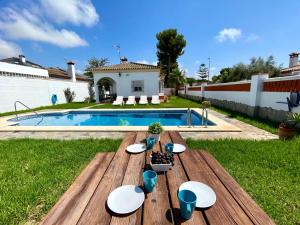 a wooden table in a backyard with a pool at Chalet Manku in Chiclana de la Frontera