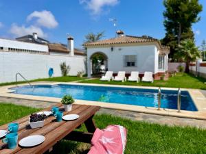a picnic table in the grass next to a pool at Chalet Manku in Chiclana de la Frontera