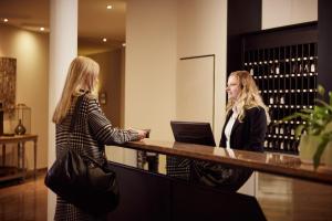 two women standing at a bar with a laptop at Van der Valk Landhotel Spornitz in Spornitz