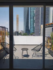 墨西哥城的住宿－Onmood Roma Norte by HiHab New Opening 2024，阳台配有2把椅子和1张桌子。