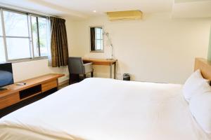 台南的住宿－友愛閤睏漫旅，卧室配有一张白色大床和一张书桌