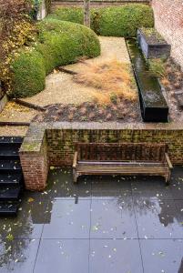 um parque com dois bancos e uma parede de tijolos em Sint-Truiden, Gootstraat 11 em Sint-Truiden