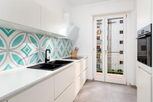 uma cozinha branca com um lavatório e uma janela em Amal - Elegant apt in Sorrento em Sorrento