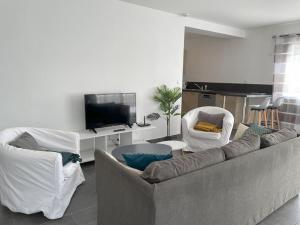 sala de estar con sofá, sillas y TV en Les Villas de Castel - Villa Les lauriers, en Castelmaurou