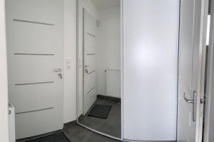 pasillo con armarios blancos y espejo en Les Villas de Castel - Villa Les lauriers, en Castelmaurou