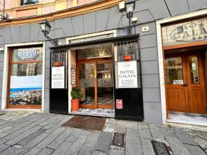 een winkel voor een gebouw met borden in de ramen bij Hotel Galata in Genua