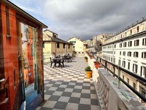 un balcón con suelo a cuadros, mesas y edificios en Hotel Galata, en Génova