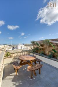 drewniany stół i ławki na patio w obiekcie Stunning 3BR Townhouse with Private Rooftop Access by 360 Estates w mieście Paola