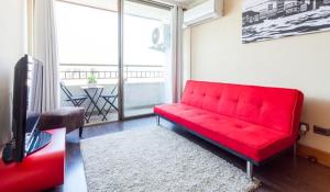 ein rotes Sofa im Wohnzimmer mit Fenster in der Unterkunft Departamento en Centro Providencia in Santiago