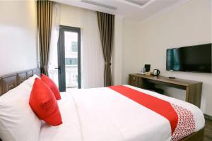 um quarto com uma cama com almofadas vermelhas e uma televisão em Hạ Long Legend Hotel em Ha Long