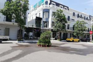 ein weißes Gebäude mit einem gelben Auto, das davor geparkt ist. in der Unterkunft Hạ Long Legend Hotel in Hạ Long