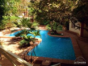 einen Blick über einen Pool mit Palmen in der Unterkunft Hotel la chaumiere in Bamako