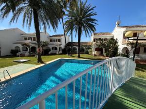 a swimming pool in front of a house with palm trees at L´Escala in Denia